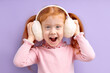 © alfa27 - Happy little girl with red hair stand wearing wireless headphones, enjoy listening to music