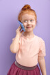 © alfa27 - Young child girl communicates on mobile phone, smiles and talks isolated on purple background