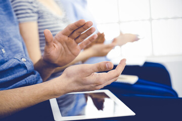  Business people clapping at meeting or conference, close-up of hands. Group of unknown businessmen and women in modern white office. Success teamwork, corporate coaching and applause concept