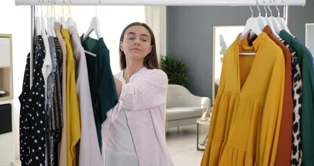 Poster - Woman choosing trendy apparel from clothes rack in boutique