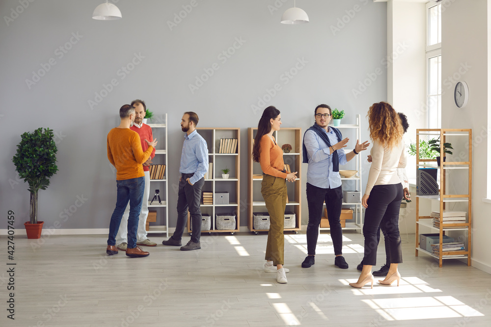 Groups of diverse people standing and talking at company networking event. Men and women meeting in modern spacious office workspace, exchanging opinions and ideas and making useful business contacts - obrazy, fototapety, plakaty 
