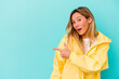 © Asier - Young mixed race woman isolated on blue background smiling and pointing aside, showing something at blank space.