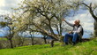 © globetrotter1 - sportlicher Mann rastet bei blühendem Obstbaum und beobachtet die Natur an sonnigem Frühlingstag