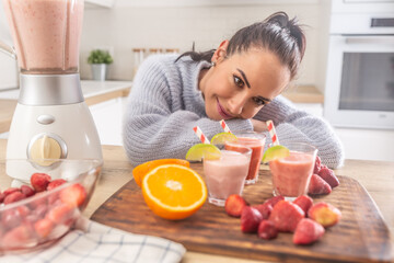 Wall Mural - Good looking woman enjoying her home made fruit smoothies in the kitchen