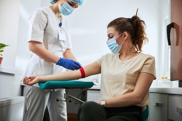 Experienced phlebotomist preparing a woman for blood draw