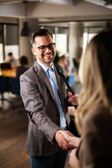 Businesswoman and businessman discussing work in office. Two friends handshake in office.