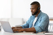 © Prostock-studio - Black millennial man in headset working remotely with laptop at home office