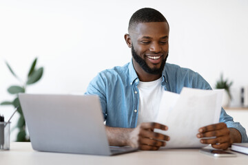 Wall Mural - Cheerful Young Black Entrepreneur Working With Papers In Modern Office