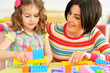 © aletia2011 - Cute little girl and her mother playing colorful plastic blocks together in her room