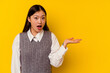 © Asier - Young chinese woman isolated on yellow background impressed holding copy space on palm.