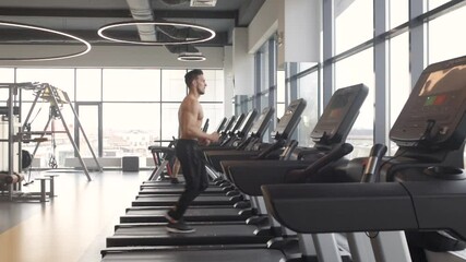 Sticker - young athletic man runs on a treadmill in the gym. cardio training on running machine