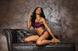 © Igor Link - Sexy young woman with long legs sitting on a dark brown leather sofa