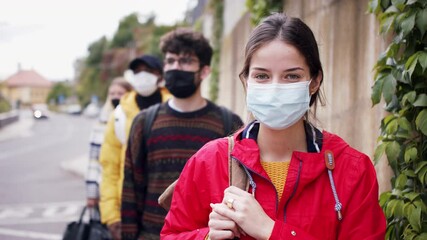 Wall Mural - Young people standing outdoors in town, looking at camera. Coronavirus and safe distance concept.