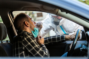 Medical worker in PPE performing drive-thru COVID-19 test