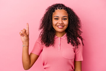 Young african american woman isolated on pink background showing number one with finger.