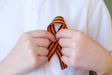 orange and black striped ribbon symbol on May 9 in hands isolated on white background. Victory Day