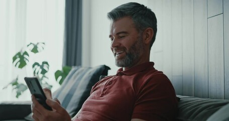 Wall Mural - Positive caucasian grey-haired millennial adult male using mobile phone receiving fun messages answering friend typing on screen. Social media. Communications.