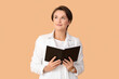 © Pixel-Shot - Beautiful young woman with book on color background