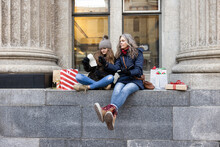 Mother And Teen Daughter Check Christmas Shopping List On City Ledge