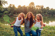 © maryviolet - Mother's day. Family having fun after playing badminton by summer river. Mother laughing and grimacing with daughters