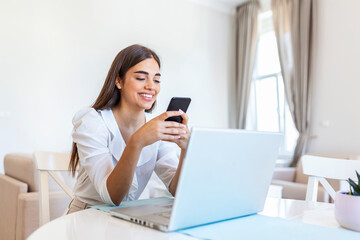 Smiling young woman study at home using laptop and mobile phone, online education e-learning concept, Young business woman having conference call with client on laptop.