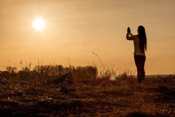 Wall Mural - Woman praying on the background of a sunny sunset .