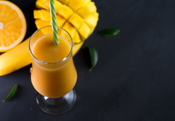 Wall Mural - High glass of smoothie cocktail with mango. Exotic healthy Breakfast copy space , dark table