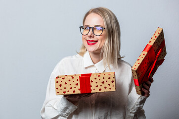 Sticker - Portrait of surprised blonde in white shirt with gift box on white background