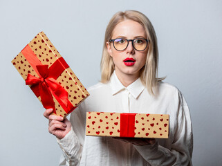 Poster - Portrait of surprised blonde in white shirt with gift box on white background