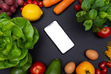 Fototapeta Kuchnia - telefon z białym ekranem i miejscem na tekst, otoczony warzywami i owocami, zdrowa dieta i odżywianie