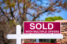 SOLD With Multiple Offers Real Estate Sign Near Purchased House Indicates Hot Seller's Market In The Desired Neighborhood. Blurred Outdoor Background