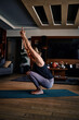 © chika_milan - A woman practicing yoga at home. A woman in a garland yoga pose. Yoga practicing at home during a corona virus outbreak.