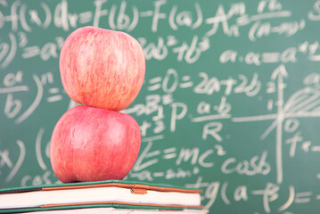 Books and red apples in front of the blackboard
