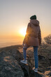 © Tishina - Girl in a jacket and a hat on the mountain during sunset