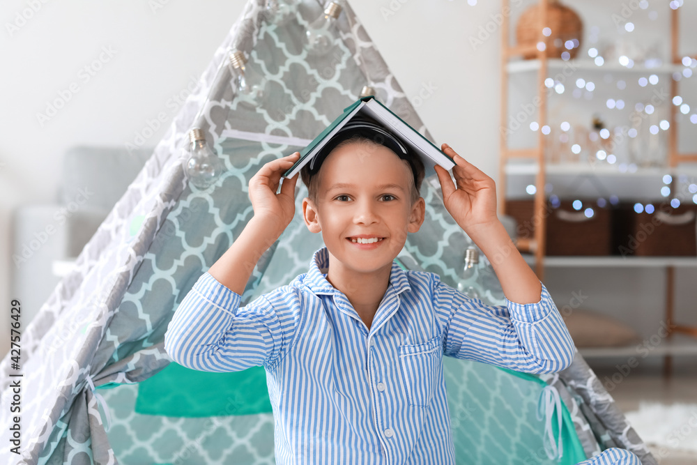 Cute little boy with book at home