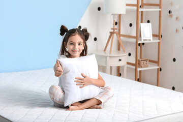 Wall Mural - Morning of little girl showing thumb-up while sitting on bed with comfortable mattress