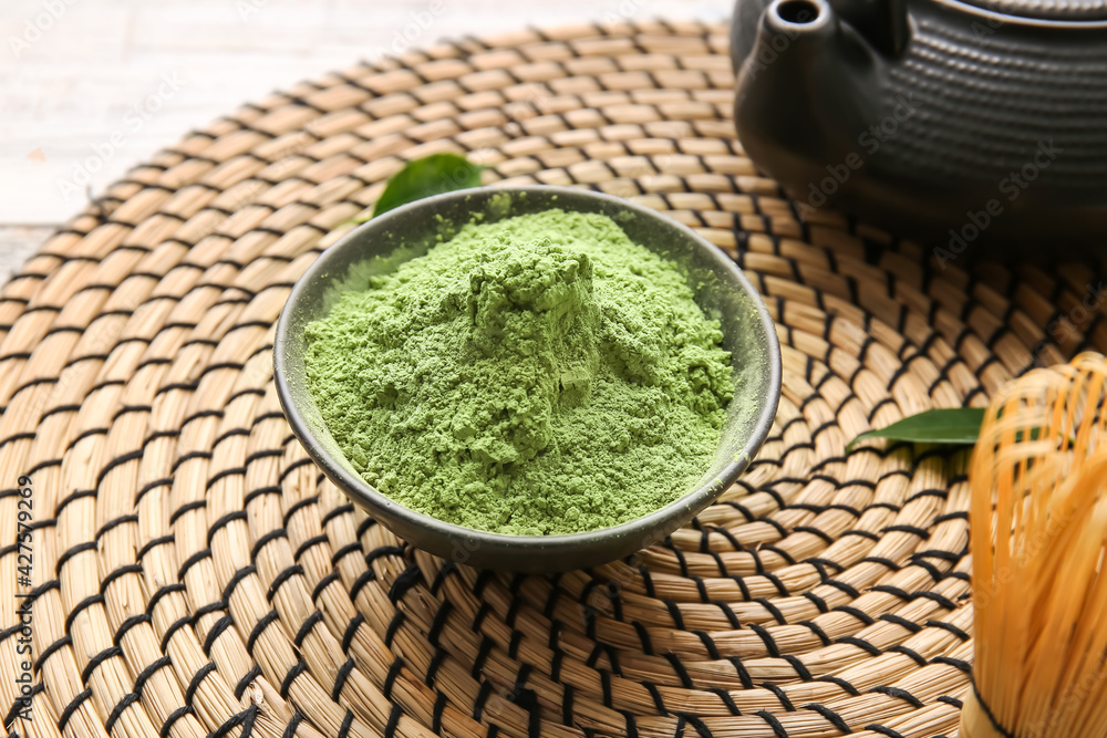 Bowl with powdered matcha tea on wicker mat