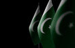 Small national flags of the Pakistan on a black background