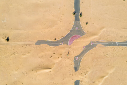 Birds eye view of a roundabout road covered by sand in the desert