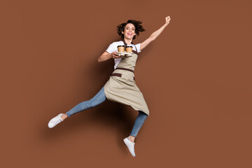 Sticker - Full body portrait of excited cheerful lady hold coffee cups raise fist up flying isolated on brown color background