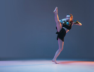 Young female MMA fighter training isolated over blue background in neon light