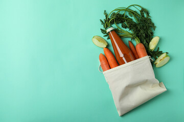 Bag with bottle of apple - carrot juice and ingredients on mint background