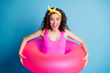 Sticker - Photo of young excited curly girl happy positive smile hold pink swimming circle isolated over blue color background