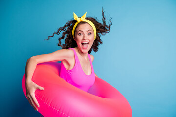 Sticker - Photo of young excited girl happy positive smile hold pink float circle ready swim isolated over blue color background