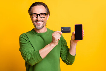 Sticker - Photo of man showing plastic debit card phone screen empty space wear glasses green sweater isolated yellow color background