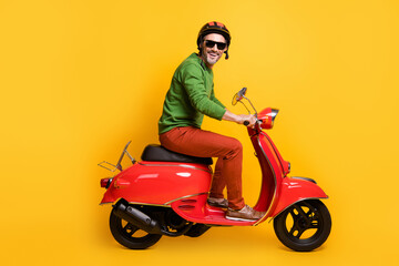 Poster - Photo of man drive bike wear helmet sunglass green pullover pants footwear isolated yellow color background