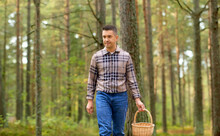 Mushroom Picking Season And Leisure People Concept - Happy Middle Aged Man With Wicker Basket Walking In Autumn Forest