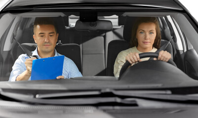 Wall Mural - driver courses, exam and people concept - young woman and driving school instructor with clipboard in car