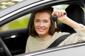 Wall Mural - driving, safety and people concept - young woman or female driver sitting in car and showing key