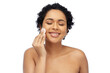 © Syda Productions - beauty, skin care and people concept - portrait of happy smiling young african american woman with bare shoulders cleaning her face with cotton pad over white background